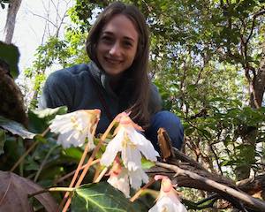 Michelle Gaynor smiling behind flowering Shortia galacifolia, who have creamy-white flowers.